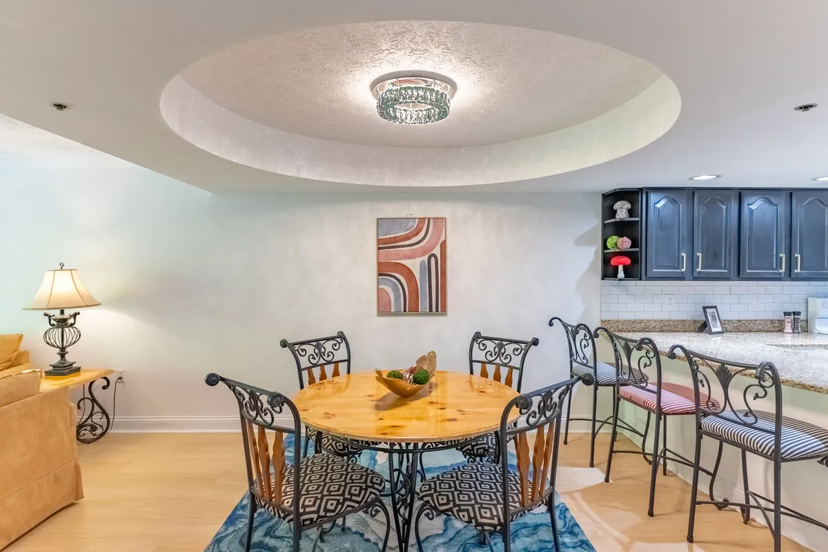 An inviting dining area with a spacious dining table under a chandelier, adjacent to a kitchen bar. The setup is perfect for sharing meals, entertaining guests, and enjoying laughter-filled gatherings.