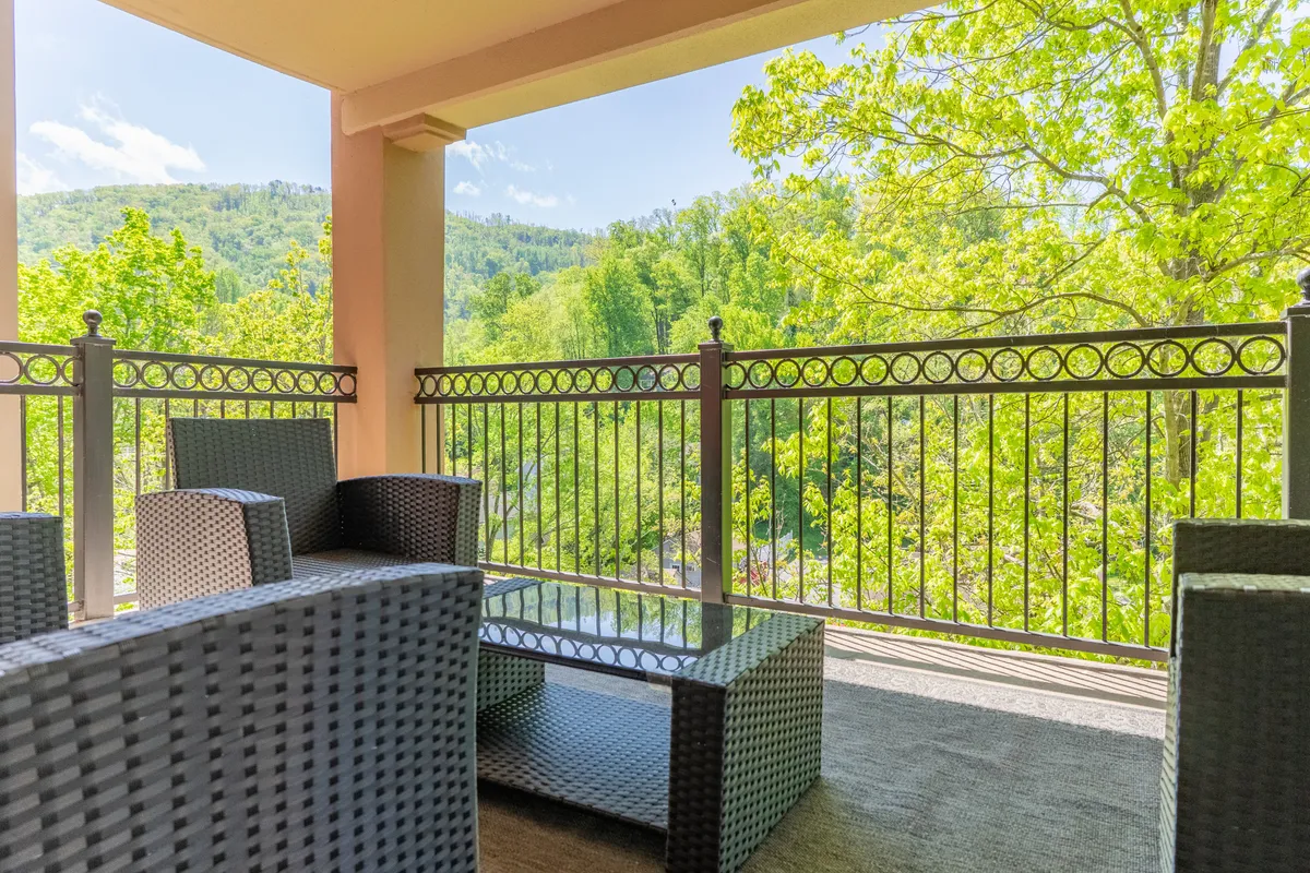 An outdoor seating area overlooks rolling mountains and is nestled among green foliage, inviting guests to relax and soak in the views. The tranquil setting suggests a seamless transition from outdoor adventure to restful comfort.