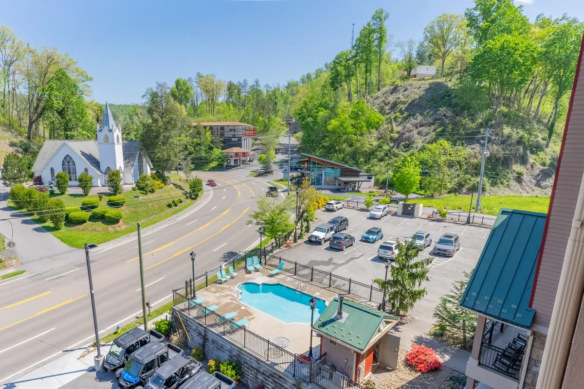 This image showcases a lively pool area surrounded by greenery, with the church and various buildings in the backdrop, and people enjoying swimming, walking, and community activities. It captures the vibrant communal atmosphere and hints at the property's proximity to local amenities and attractions.