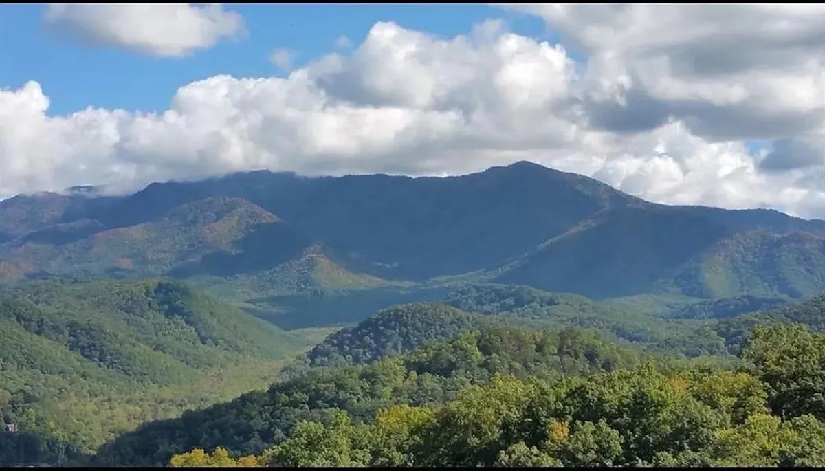 A breathtaking view of the Smoky Mountains with lush green hills and clouds drifting over the peaks, providing a scenic natural backdrop.