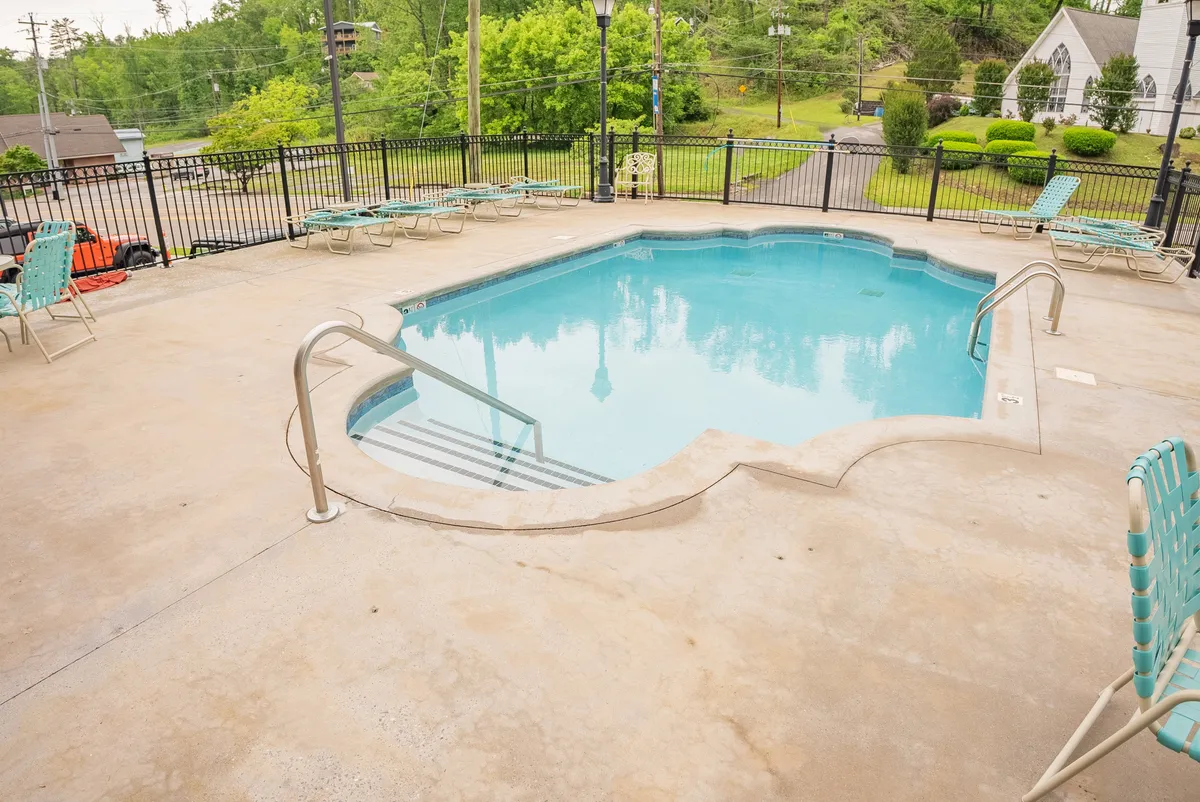 A tranquil setting featuring a crystal-clear swimming pool bordered by comfortable lounge chairs and verdant landscaping. The calm water and inviting seating evoke a resort-like atmosphere ideal for both active swims and leisurely afternoons under the sun.